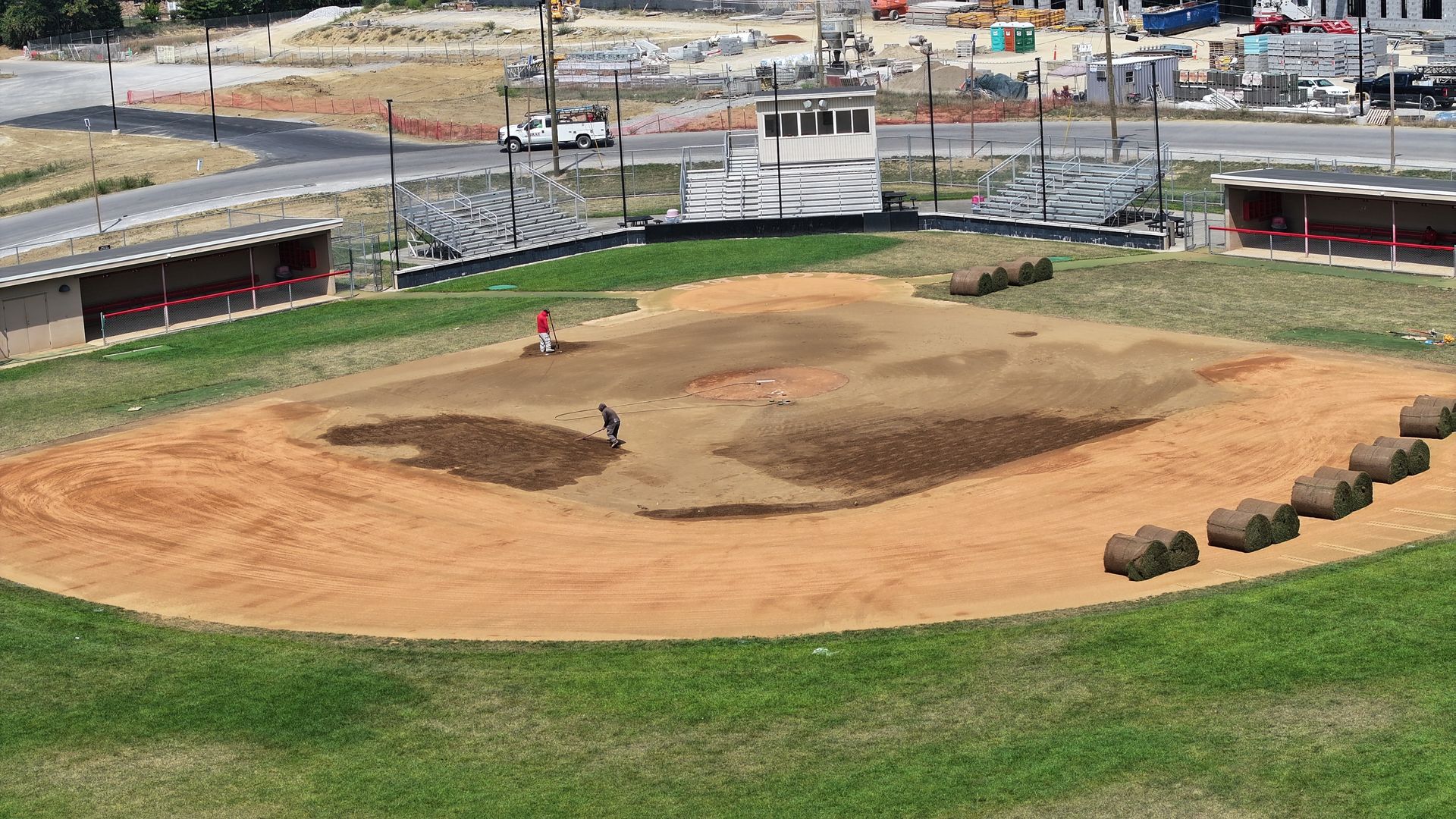 Baseball field with dirt infield, green outfield, and covered dugouts in the background