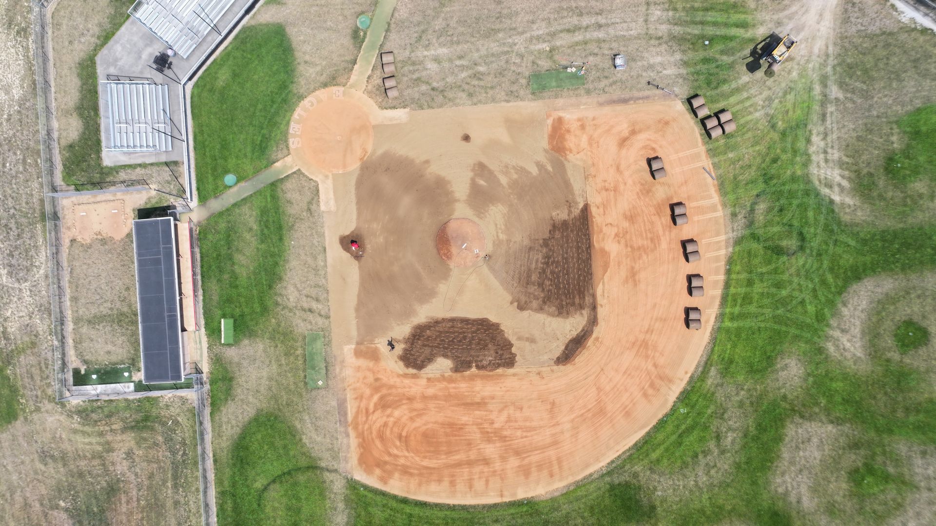 Aerial view of a baseball field with infield dirt, dugouts, and surrounding green grass.