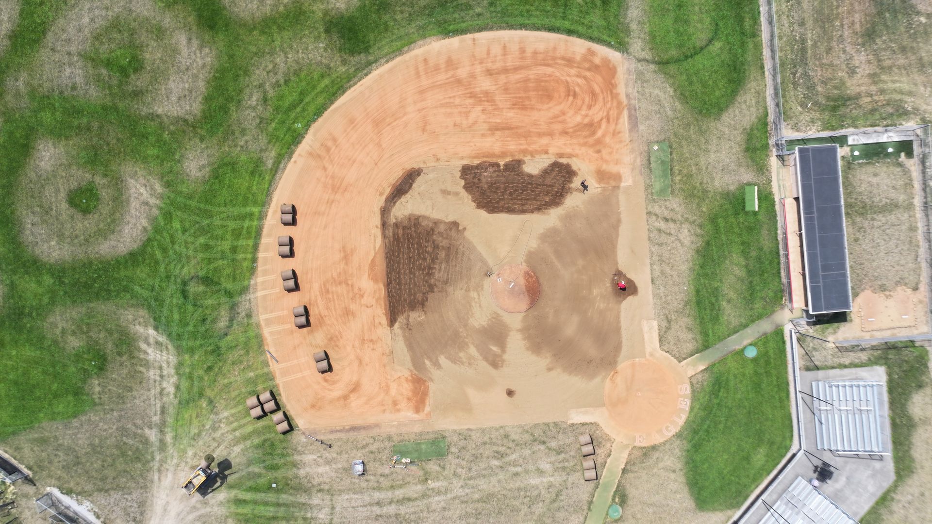 Aerial view of a dirt arena with scattered chairs and surrounding grass