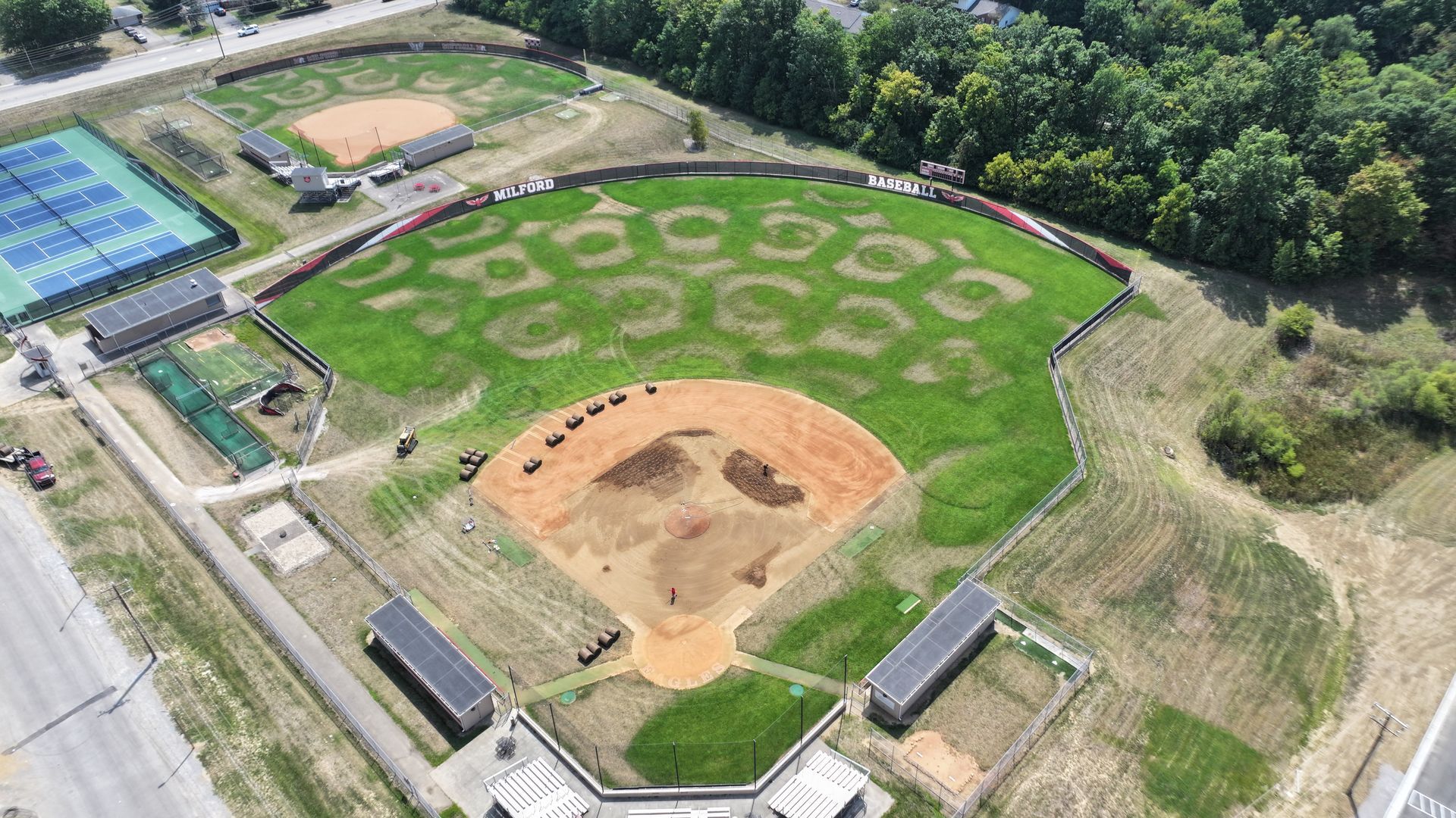 Aerial view of a baseball field and nearby sports grounds with green grass and dirt infield
