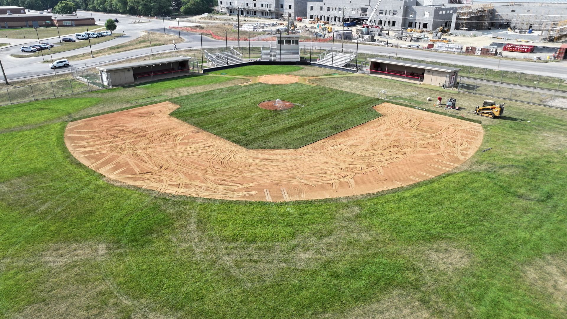 Aerial view of a baseball field under construction with a dirt infield and green grass outfield