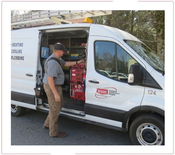 Worker loading supplies into a white utility van with open side door, parked outdoors