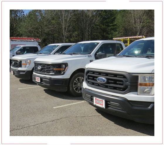 Parked white pickup trucks in a lot, viewed from the front at an angle.