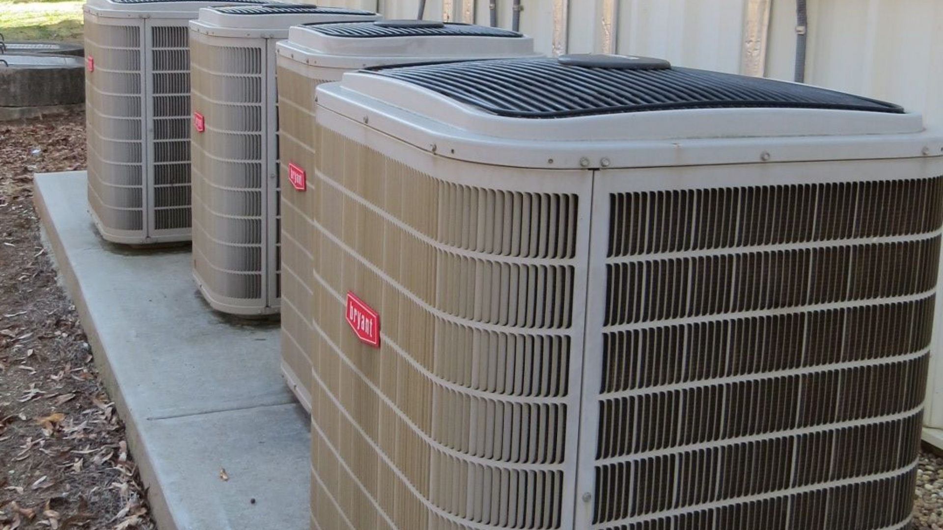 Bryant outdoor air conditioner unit with beige grille and red logo in a gravel yard