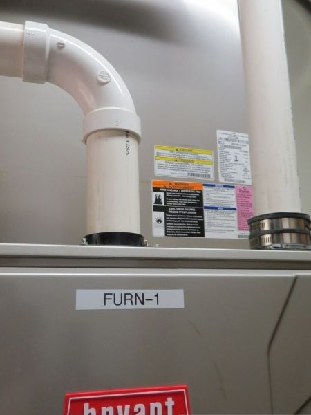 Bryant furnace with white PVC vent pipes and labels in a utility closet