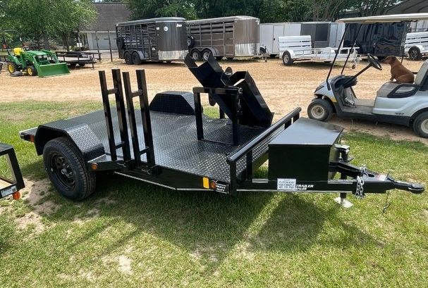 A motorcycle trailer is parked in a grassy field next to a golf cart.