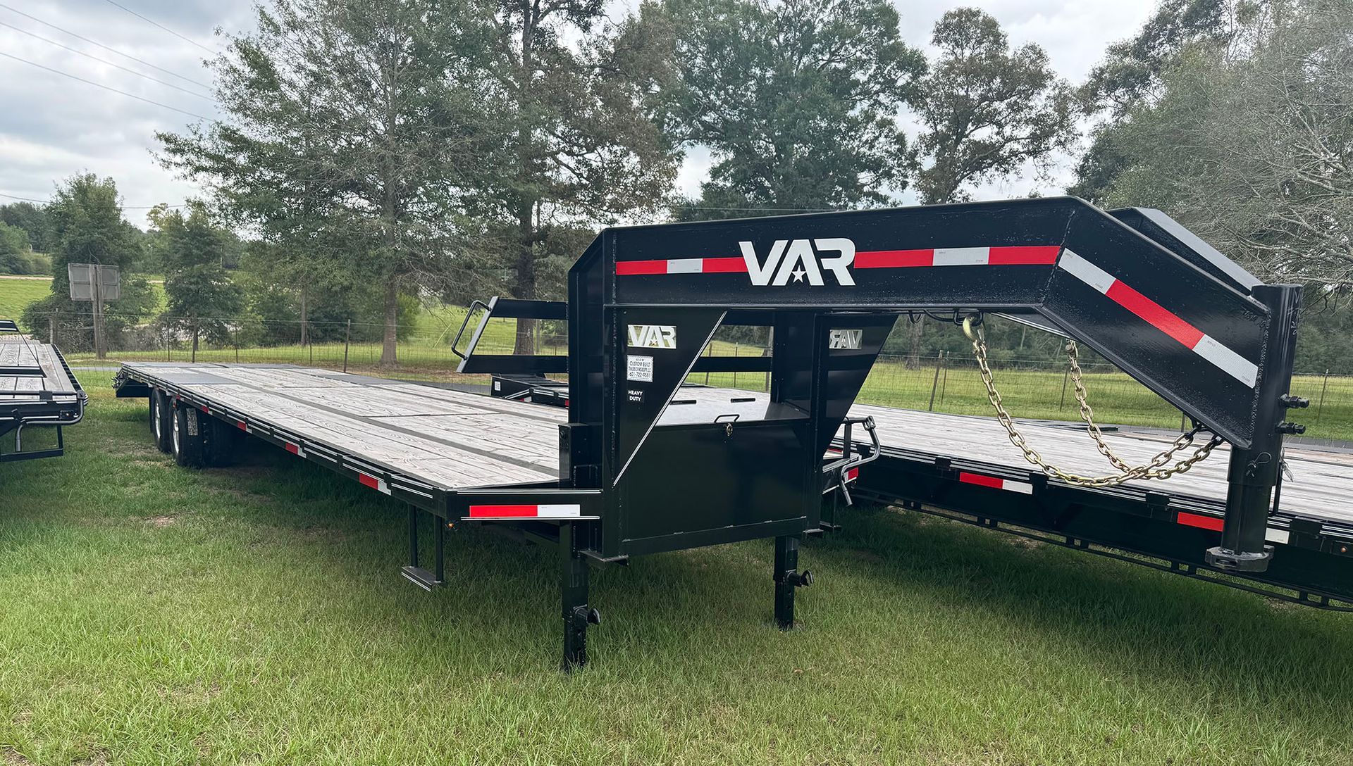 A flatbed trailer is parked in a grassy field.