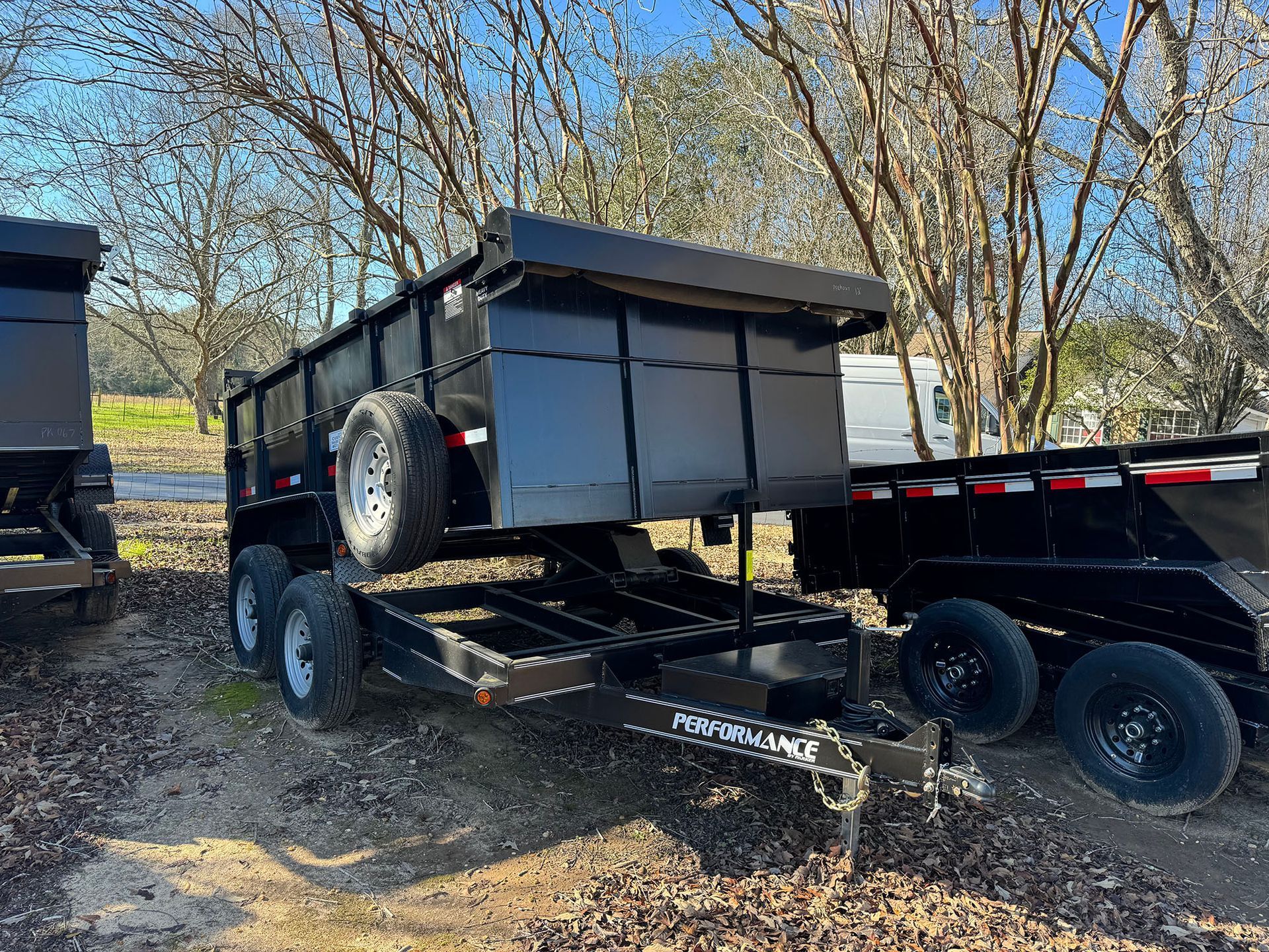 A dump trailer is parked next to a dump truck.