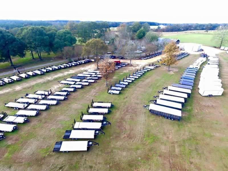 An aerial view of a row of trailers parked in a field.