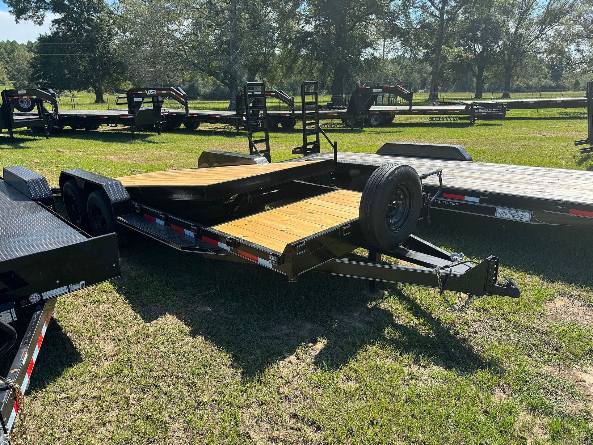 A trailer is sitting on top of a lush green field.