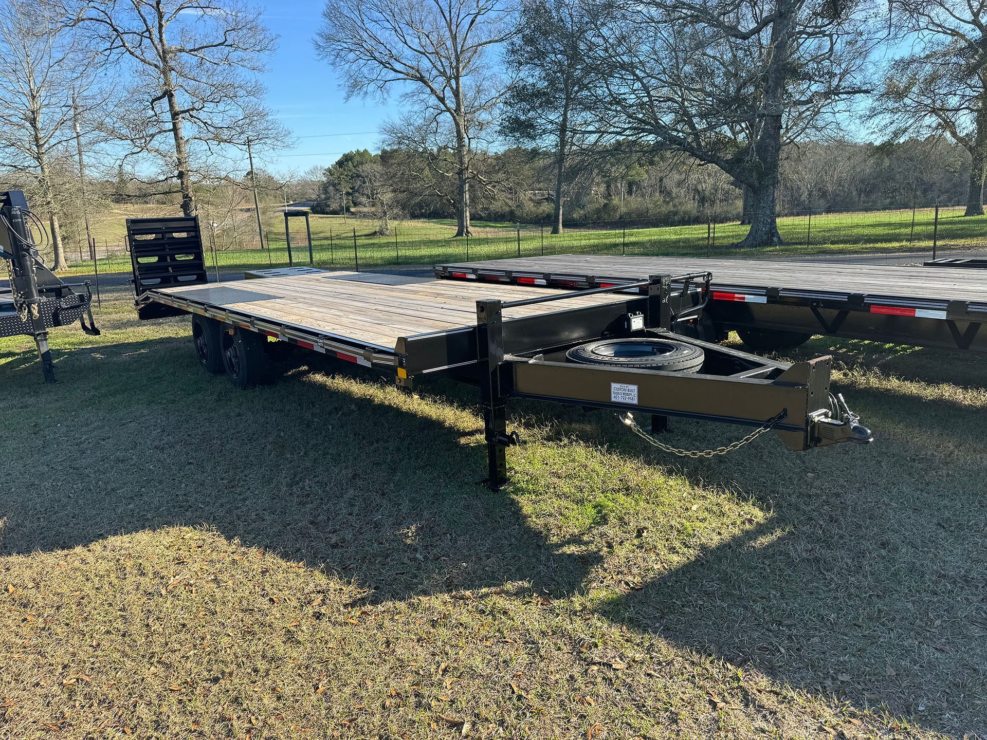 A flatbed trailer is parked in a gravel lot.