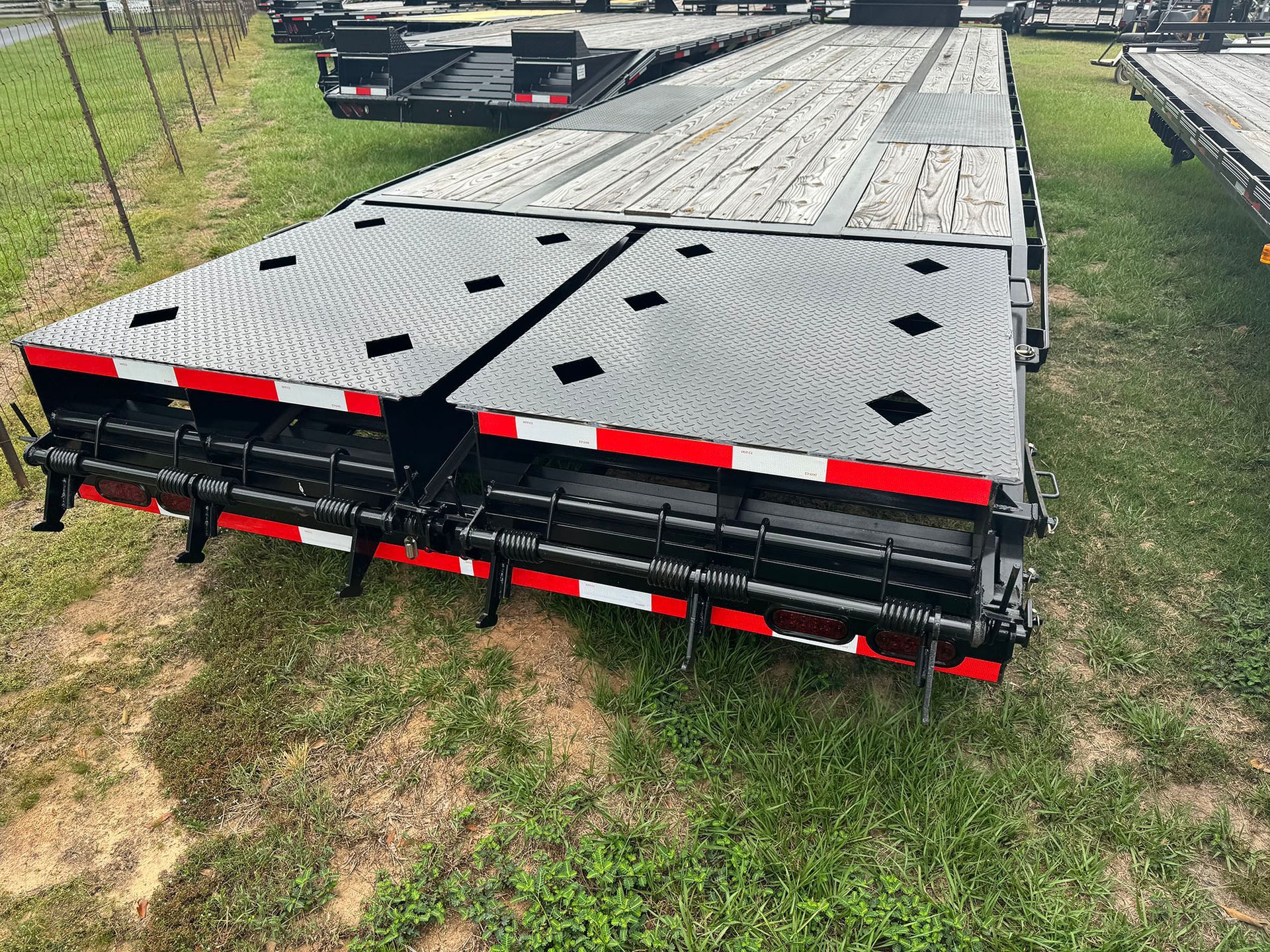 A trailer is sitting on top of a lush green field.