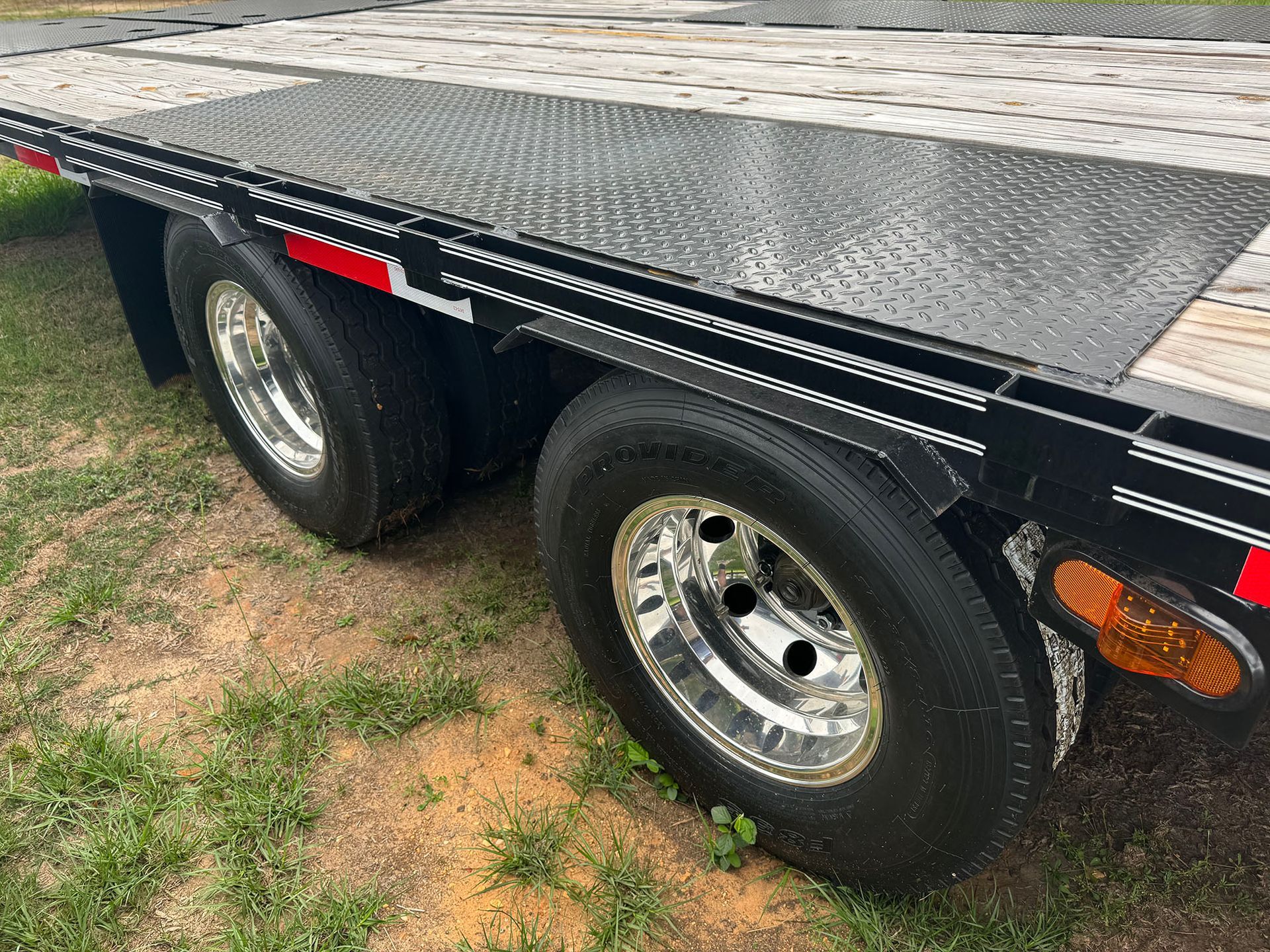 A flatbed trailer is parked in a grassy field.