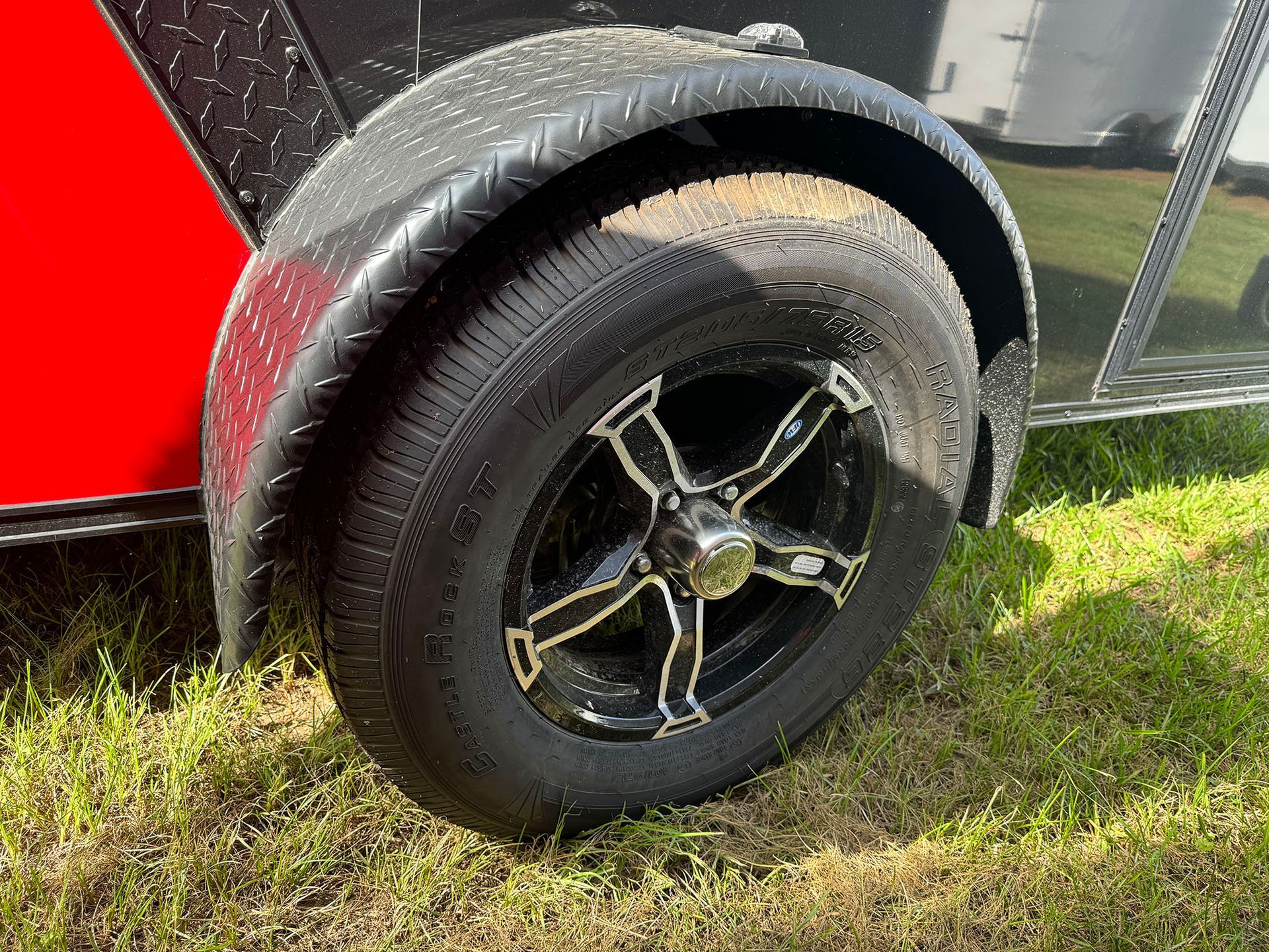 A close up of a tire on a trailer in the grass.