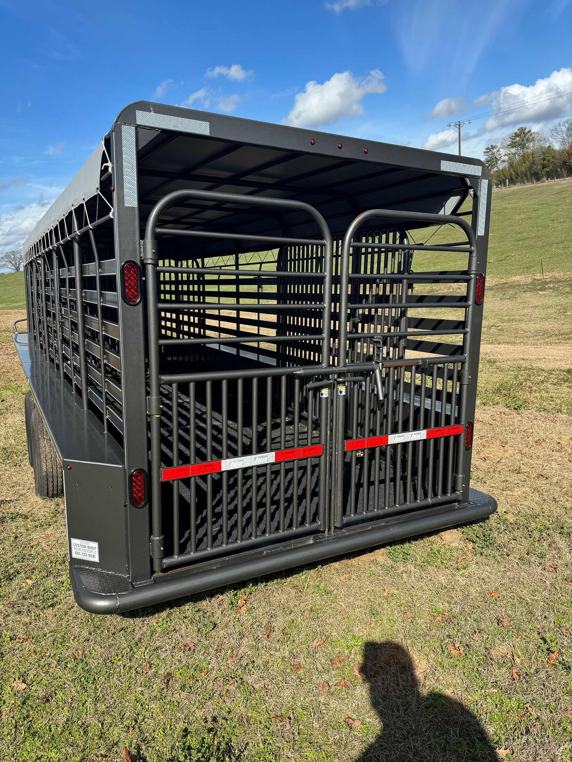 A horse trailer is parked in a grassy field.