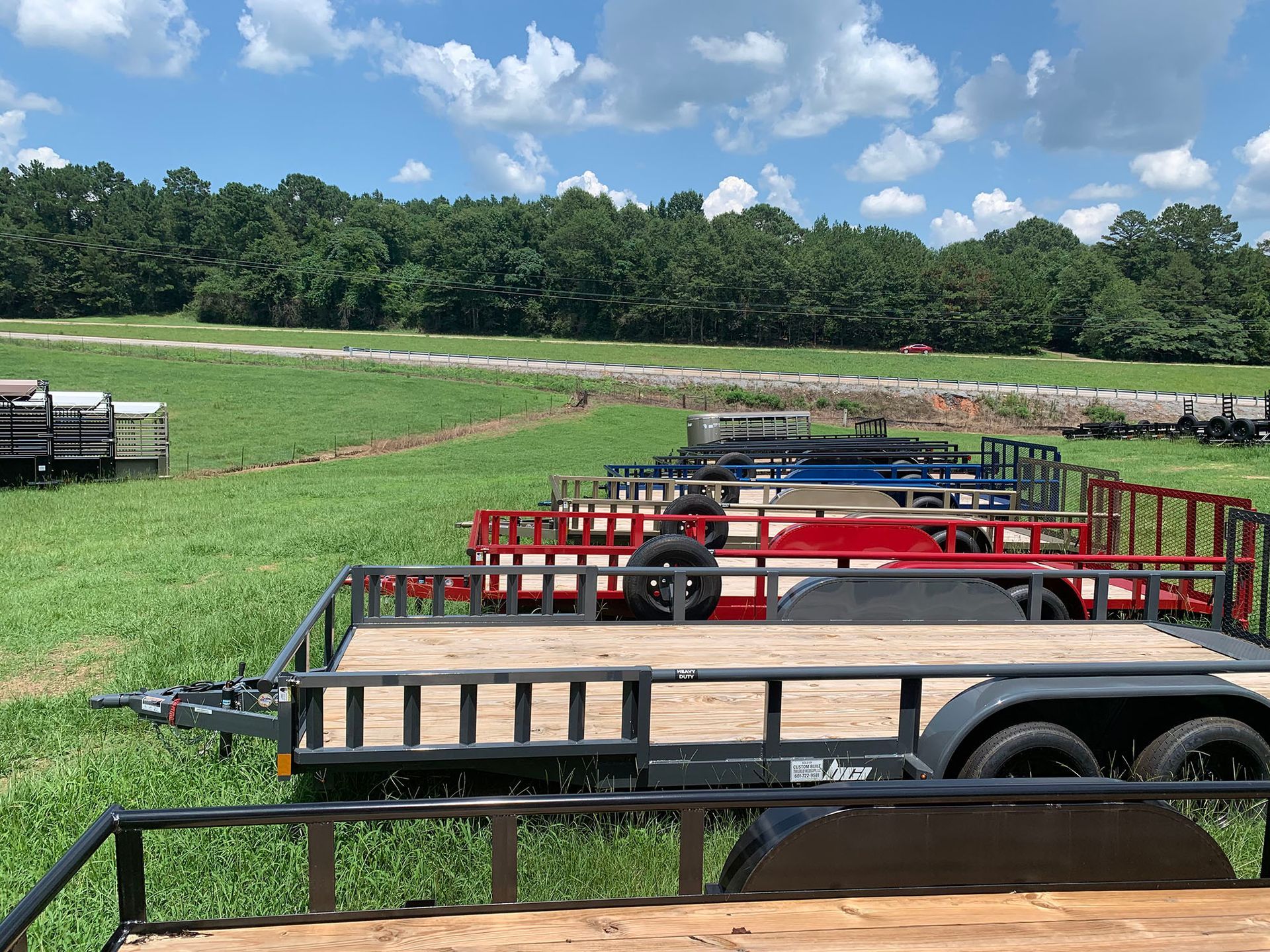 A row of trailers are parked in a grassy field.