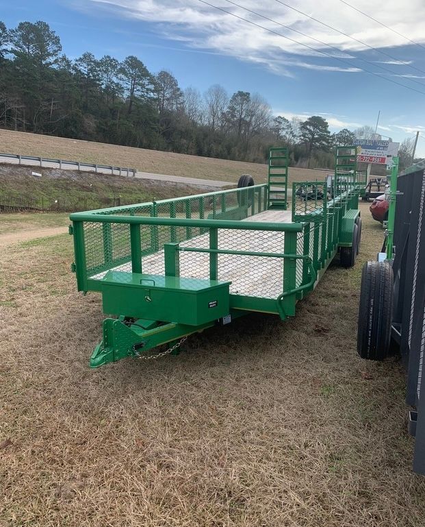 A green trailer is parked in a grassy field.