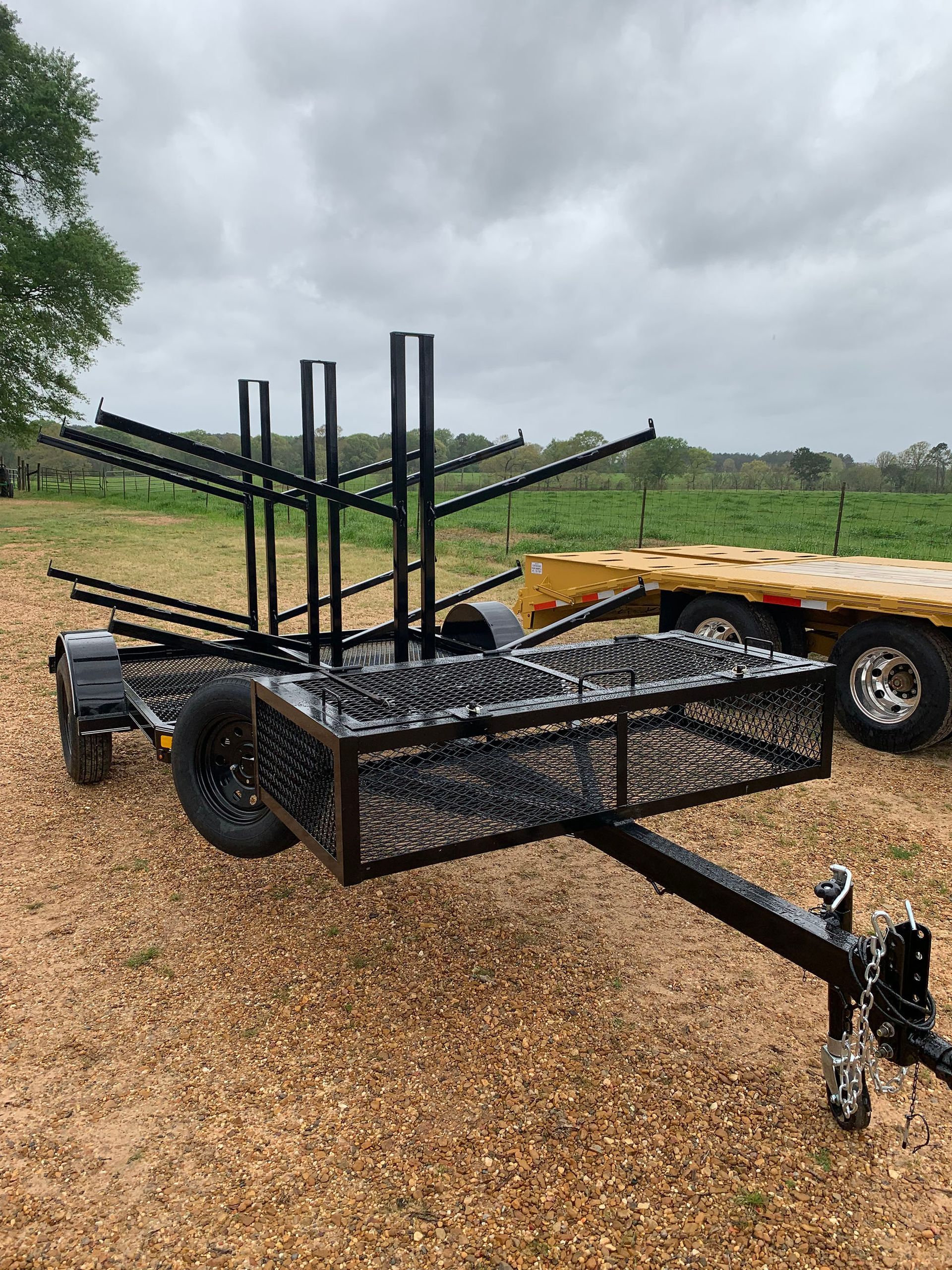 A trailer is parked in a field next to a truck.