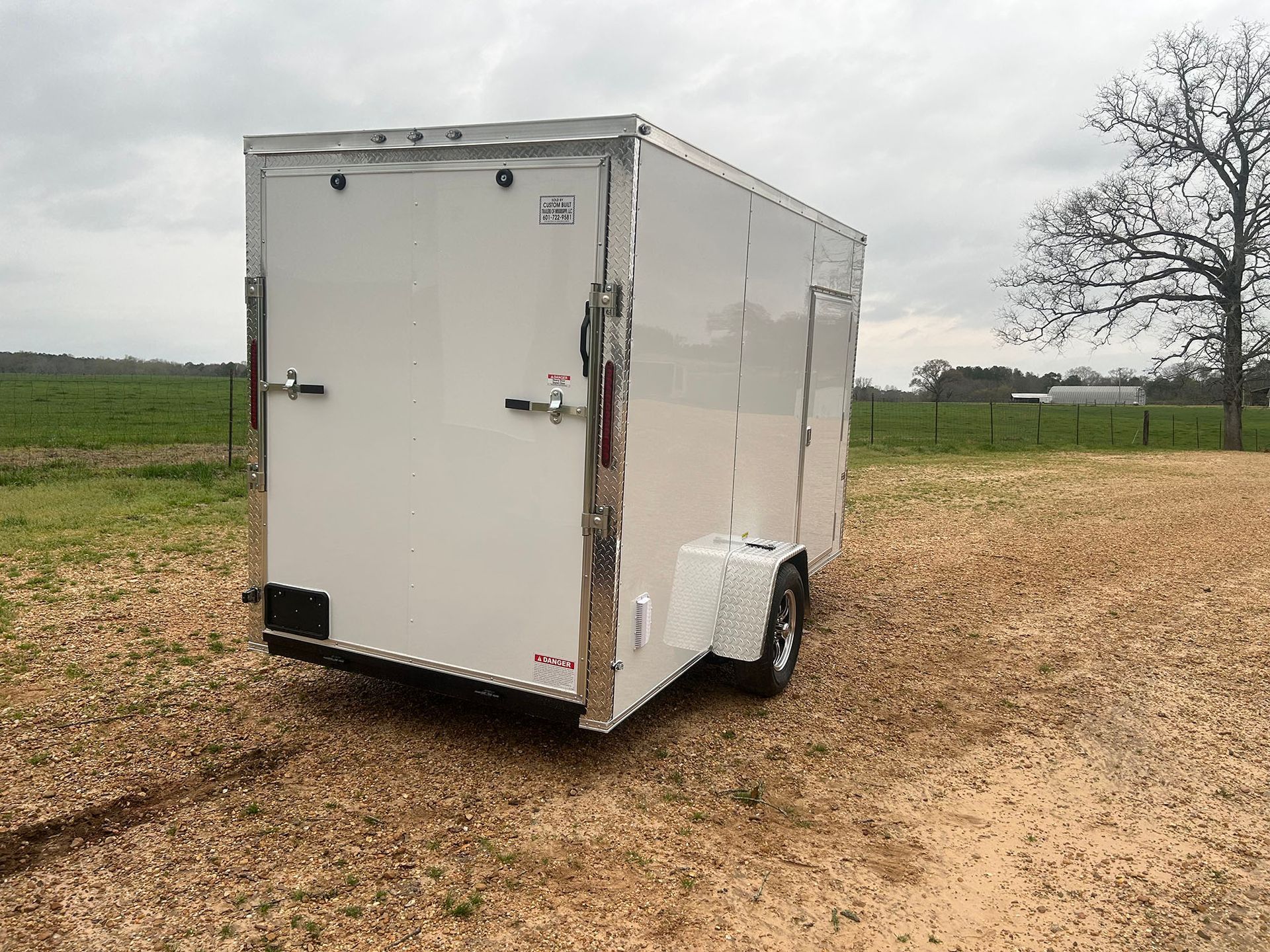 A white trailer is parked in a dirt field.