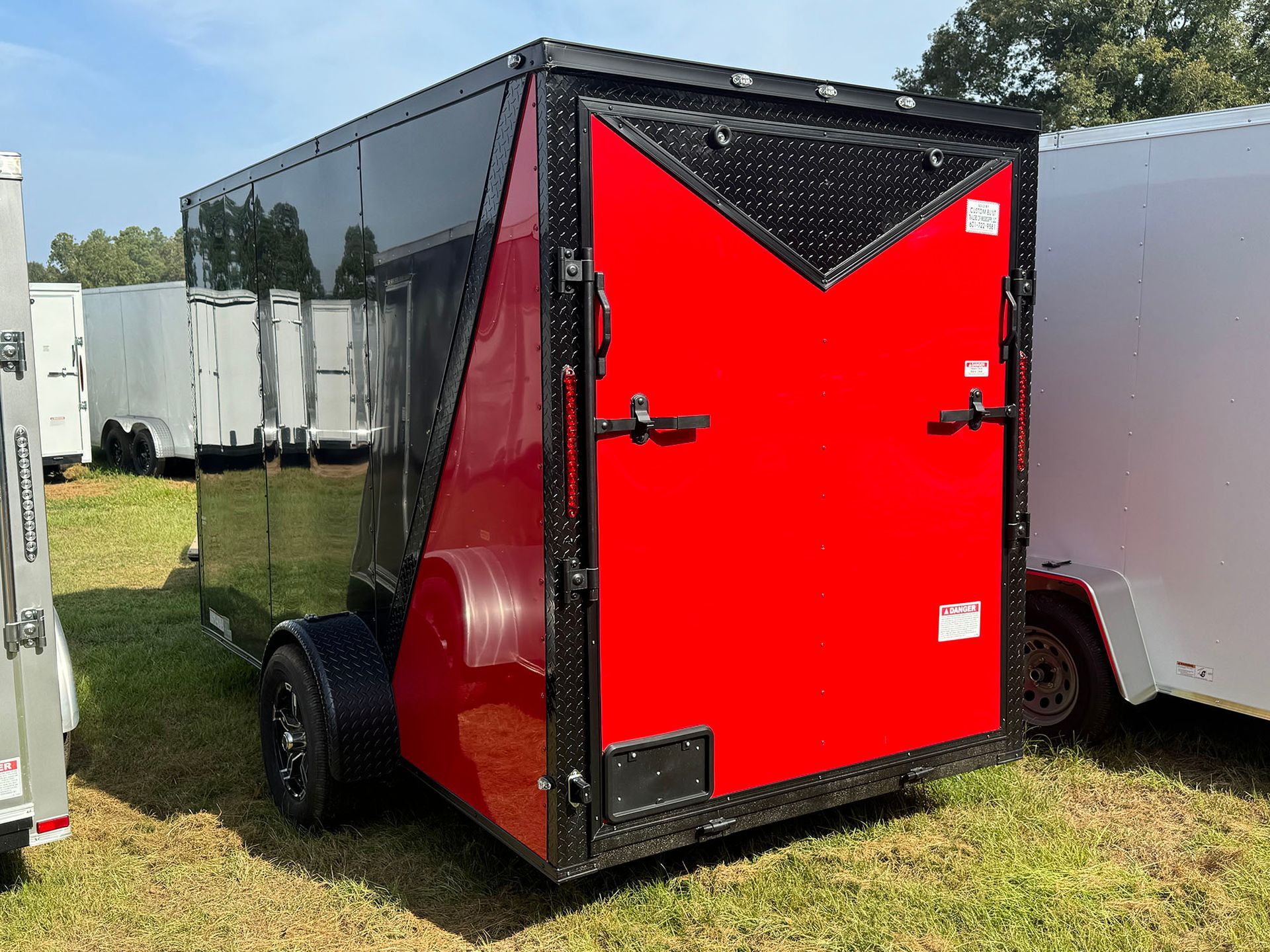 A red and black trailer is parked in a grassy field.