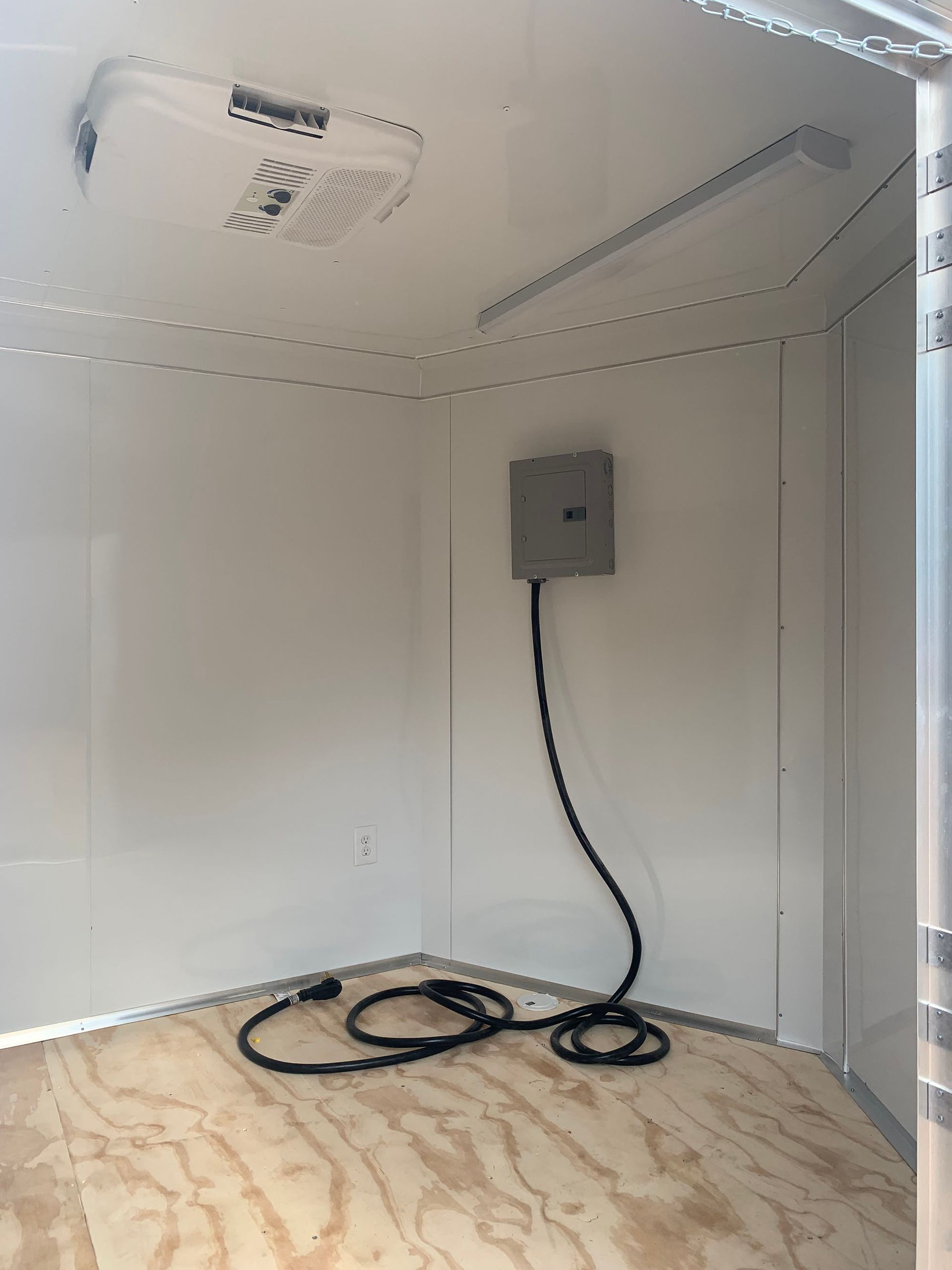 An empty room with a fan and a box on the wall.