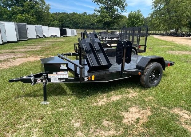 A motorcycle trailer is parked in a grassy field.