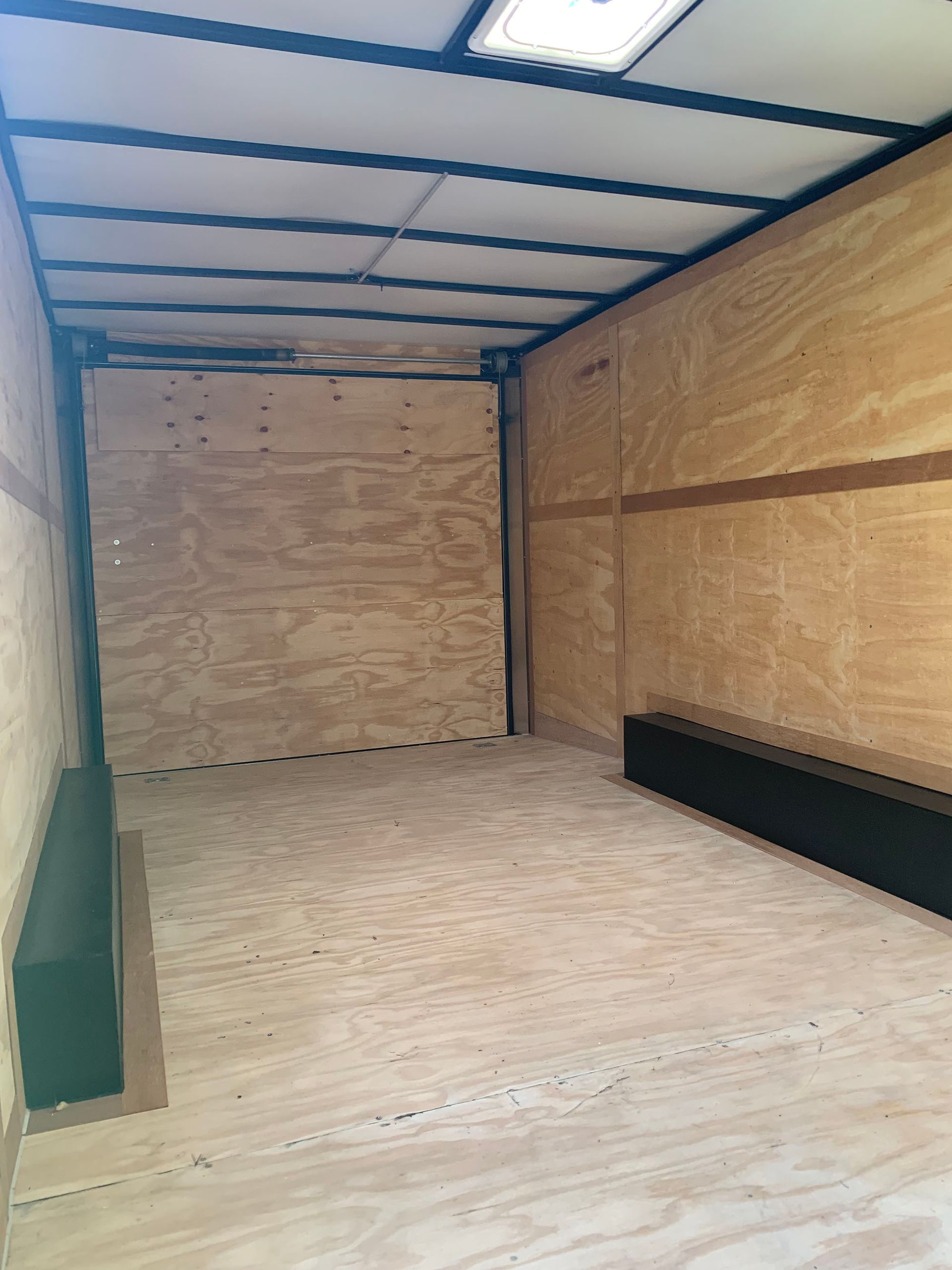 The inside of an empty trailer with a wooden floor.