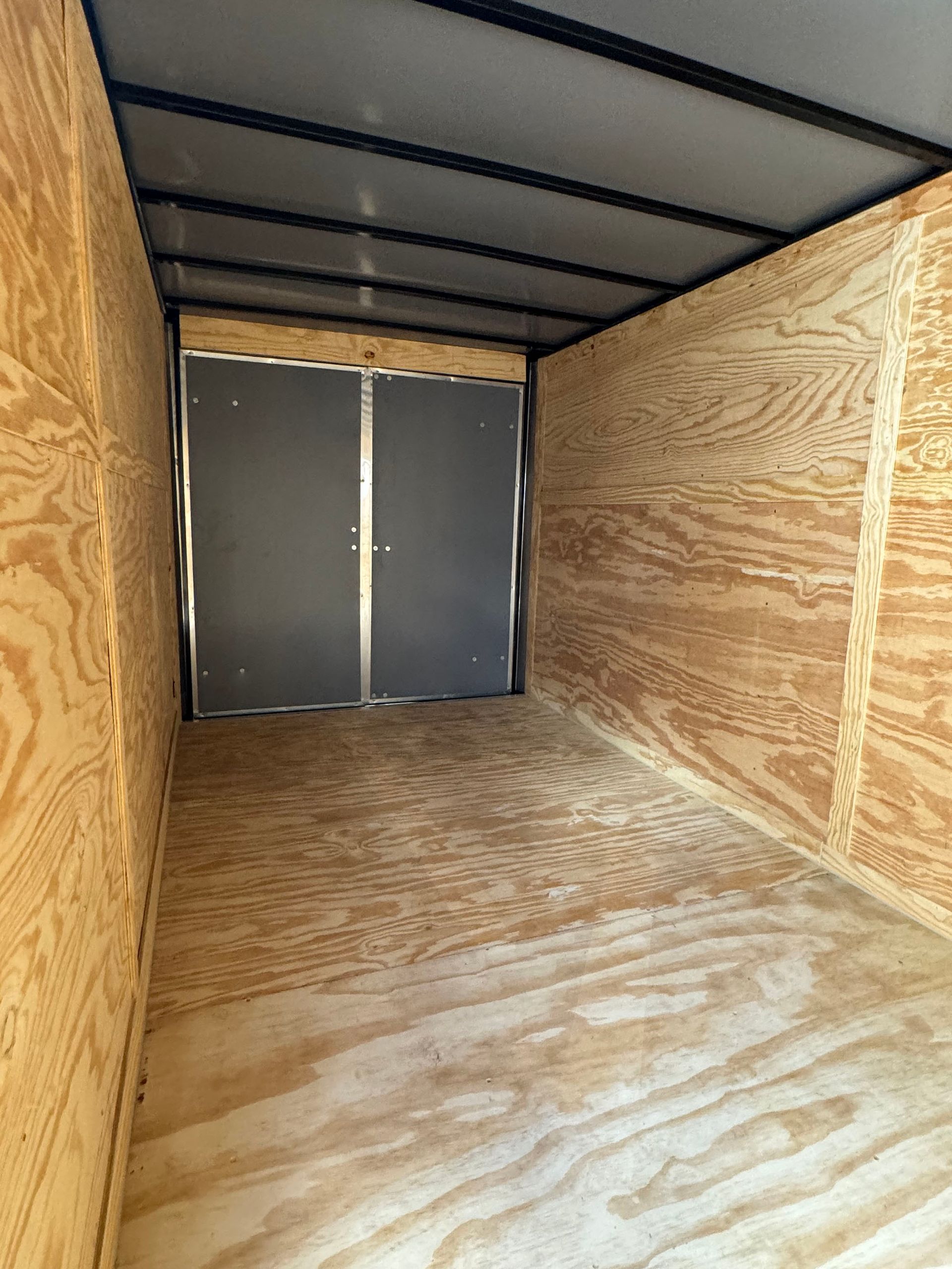The inside of a trailer with wooden walls and a gray door.