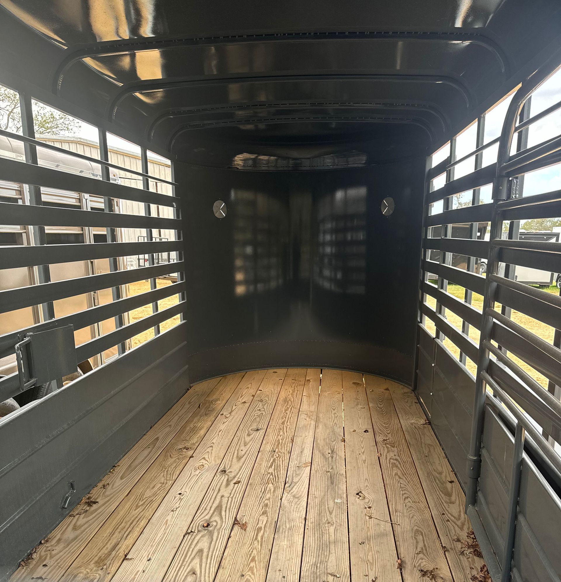 The inside of a horse trailer with a wooden floor and fences.