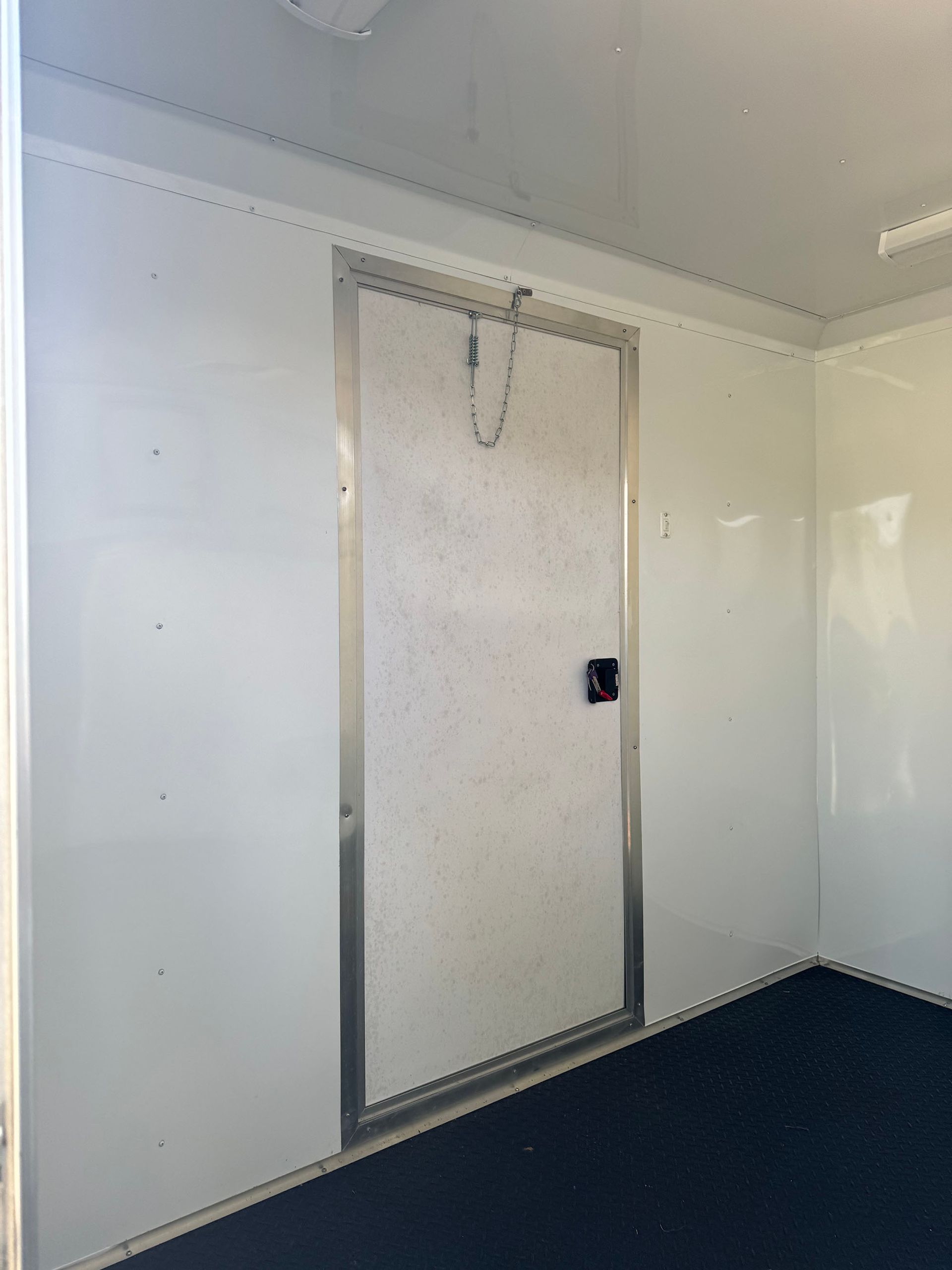 A white wall with a black door in a room.