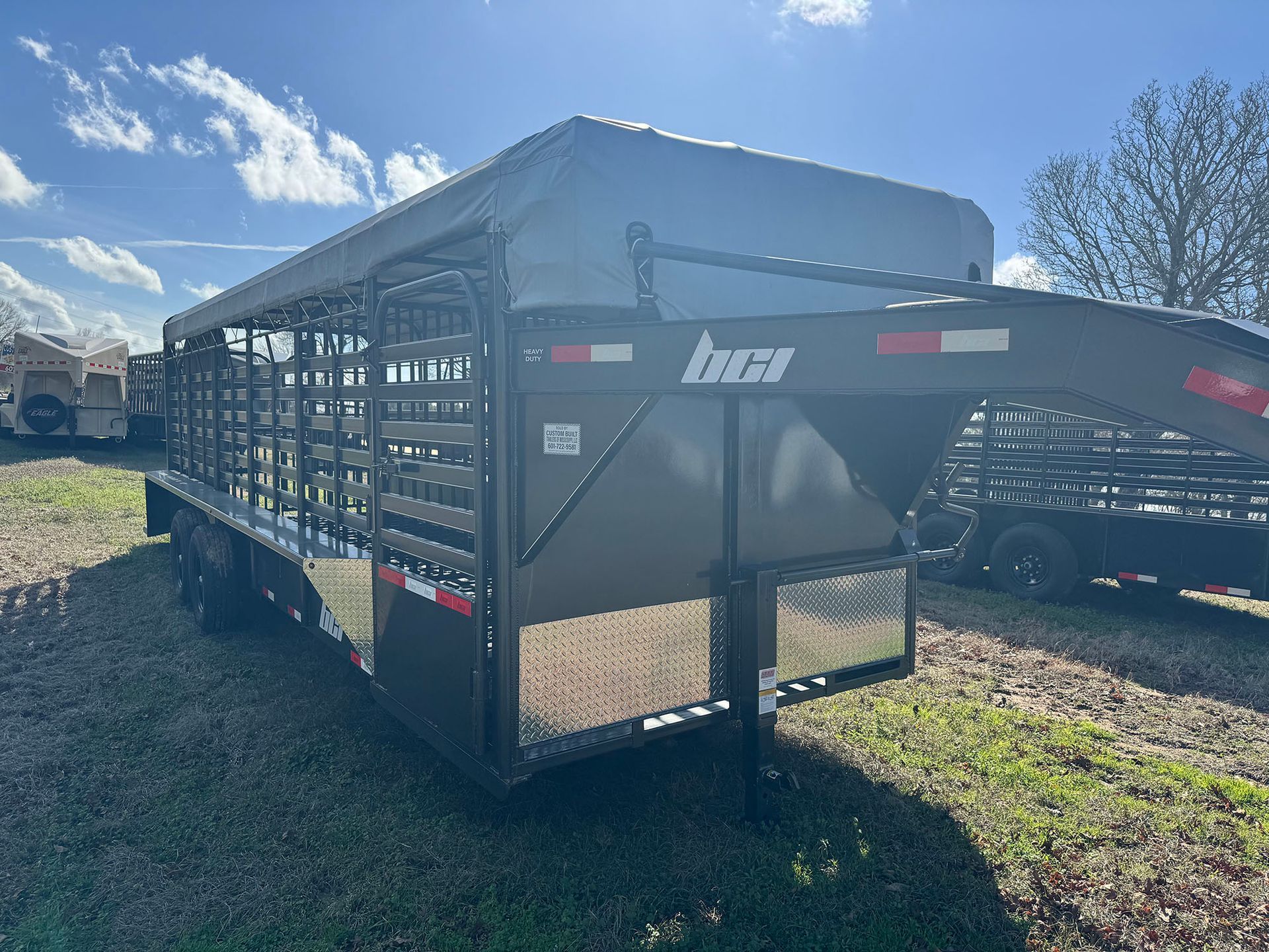 A trailer with a fence attached to it is parked in a field.