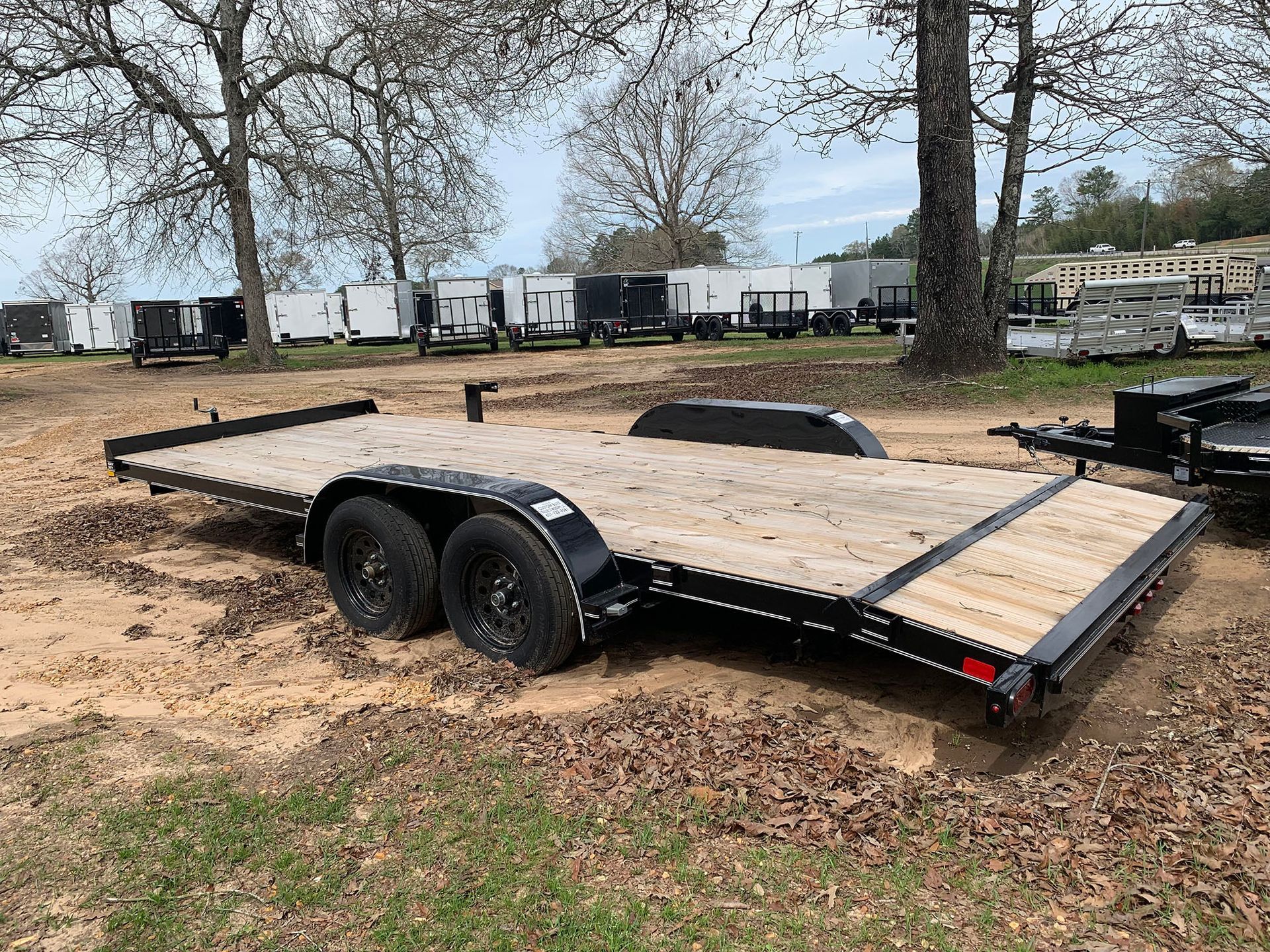 A flatbed trailer is parked in a dirt field.