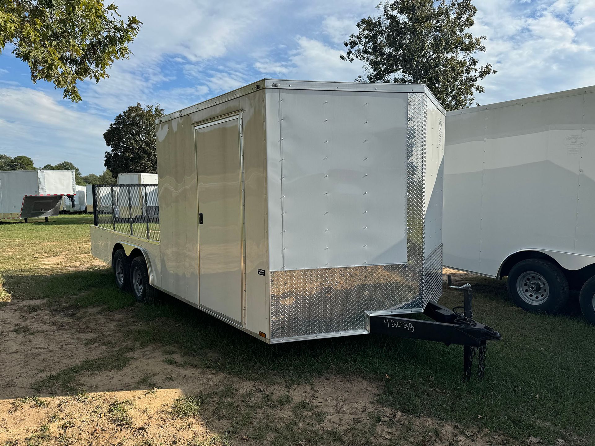 A white trailer is parked in a grassy field.