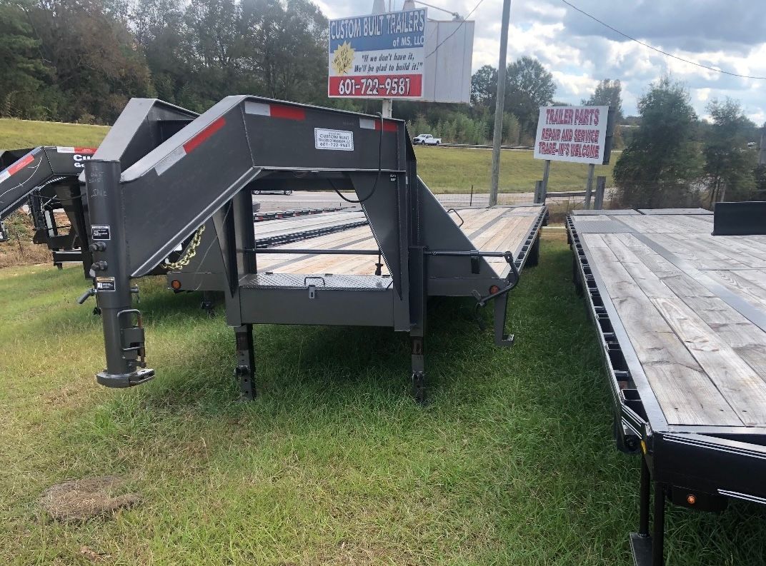 A trailer is sitting on top of a lush green field.