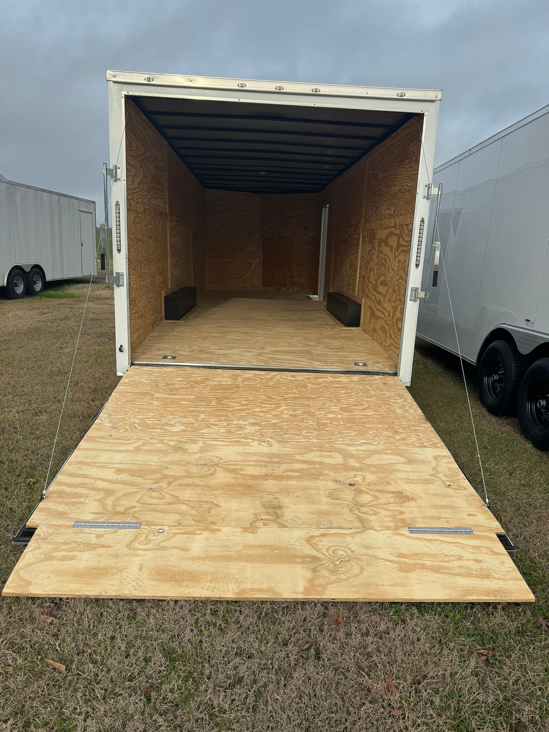 The inside of a trailer with the door open and a wooden floor.