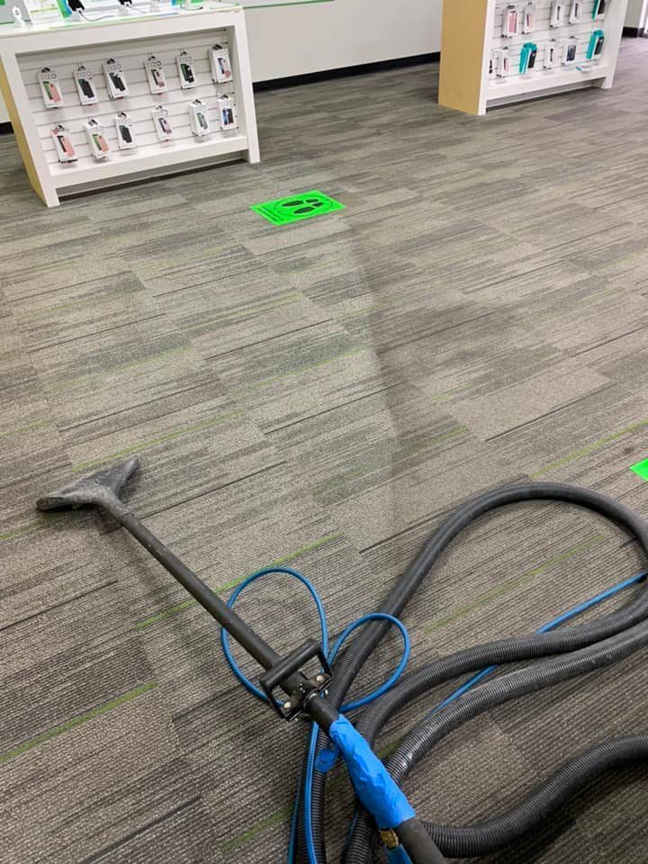 A vacuum cleaner is sitting on a carpeted floor in a store.