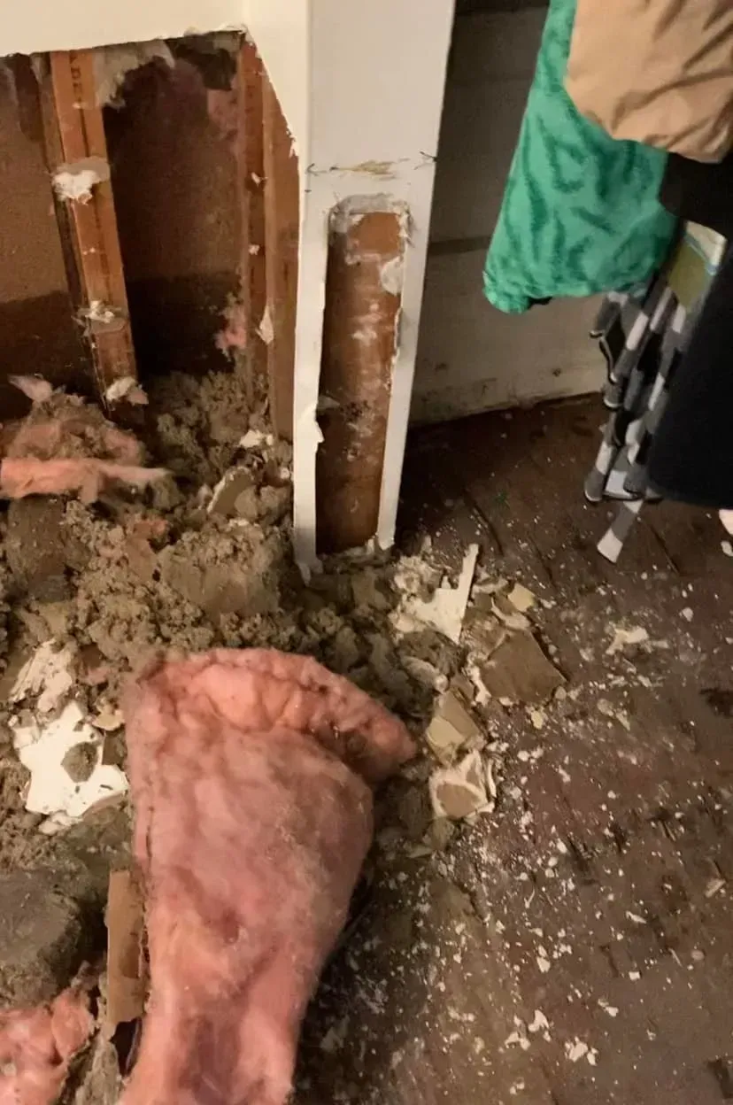 A person is standing in a room with a hole in the wall.