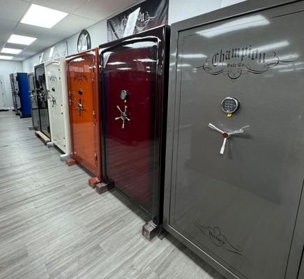 Row of colorful gun safes in a showroom, including white, orange, and gray models.