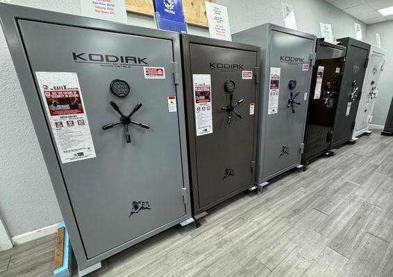 Line of Kodiak gun safes, various colors, in a retail store setting.