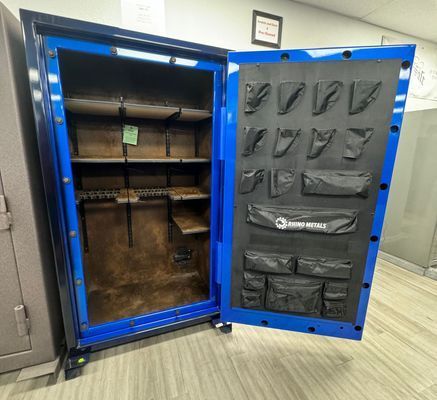 Blue gun safe interior with shelves, gun rack, and door organizer.