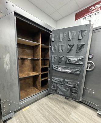 Opened Rhino gun safe with shelves and door storage, gray exterior, brown interior.