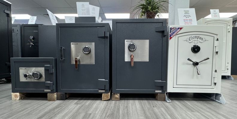 Four safes of varying sizes and colors displayed on a showroom floor.