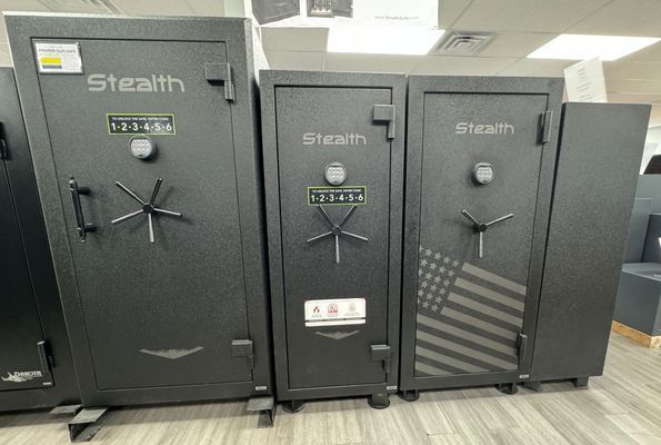 Three black Stealth gun safes with combination locks, arranged side-by-side on a showroom floor.