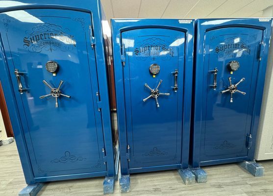 Three blue Superior gun safes side-by-side. Each has a combination lock and star-shaped handle.