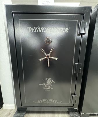 A dark gray Winchester gun safe with silver accents and a combination dial.