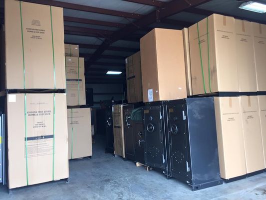Storage unit filled with stacked cardboard boxes and black metal safes.