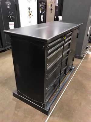 Black metal workbench with drawers, in a showroom, near safes.