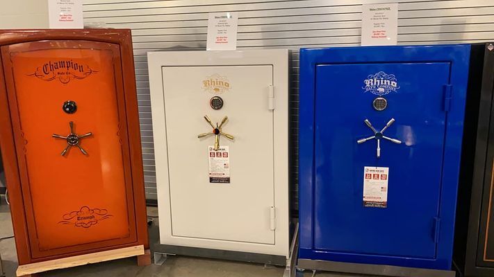 Three colorful safes: orange, white, and blue, displayed in a store setting. Each has a star-shaped handle.