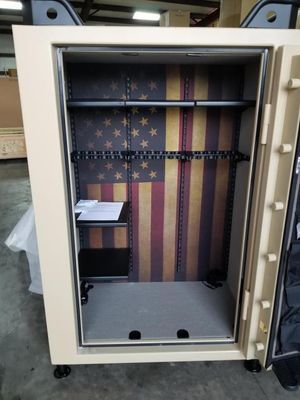 Tan gun safe interior with American flag backdrop; shelves and gun racks visible.