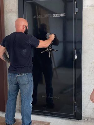 Man opening a black safe door with a combination dial, indoors.